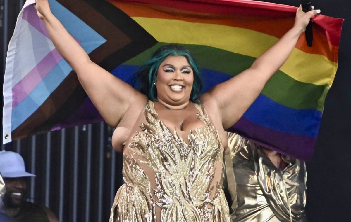 Picture of Lizzo. She is holding a pride flag whilst performing at glastonbury.